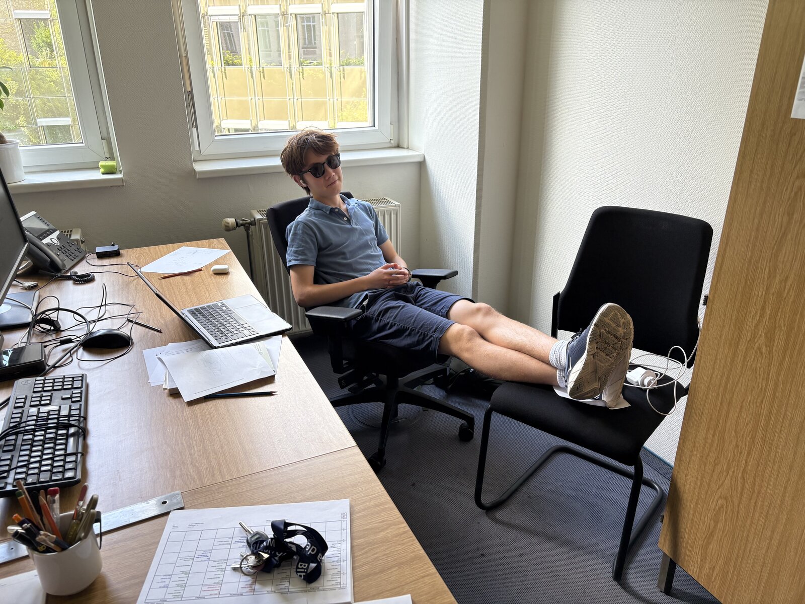 Louie Merriam reclining in an office chair at TU Berlin.